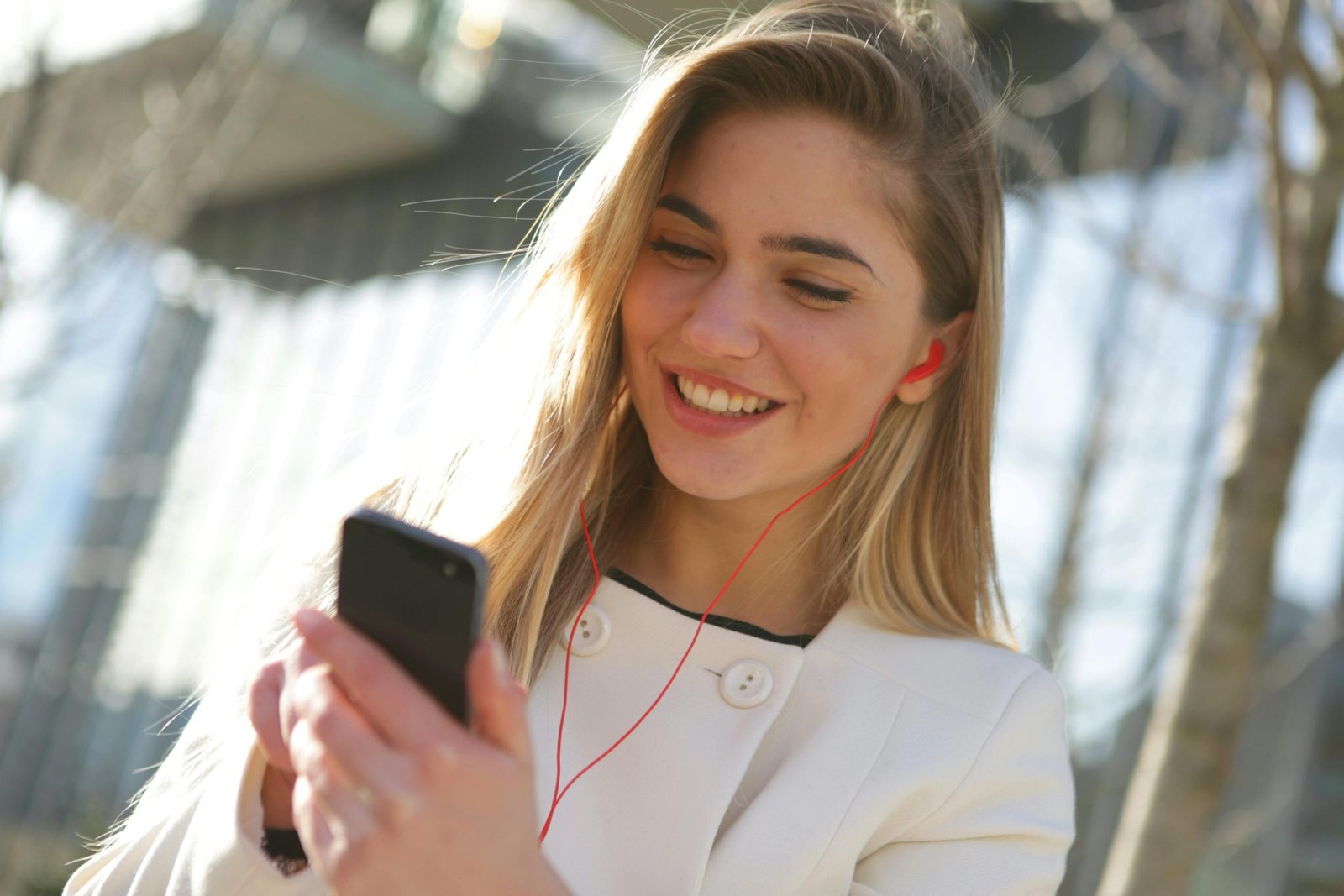 Young woman enjoying a moment with her smartphone outdoors on a sunny day.